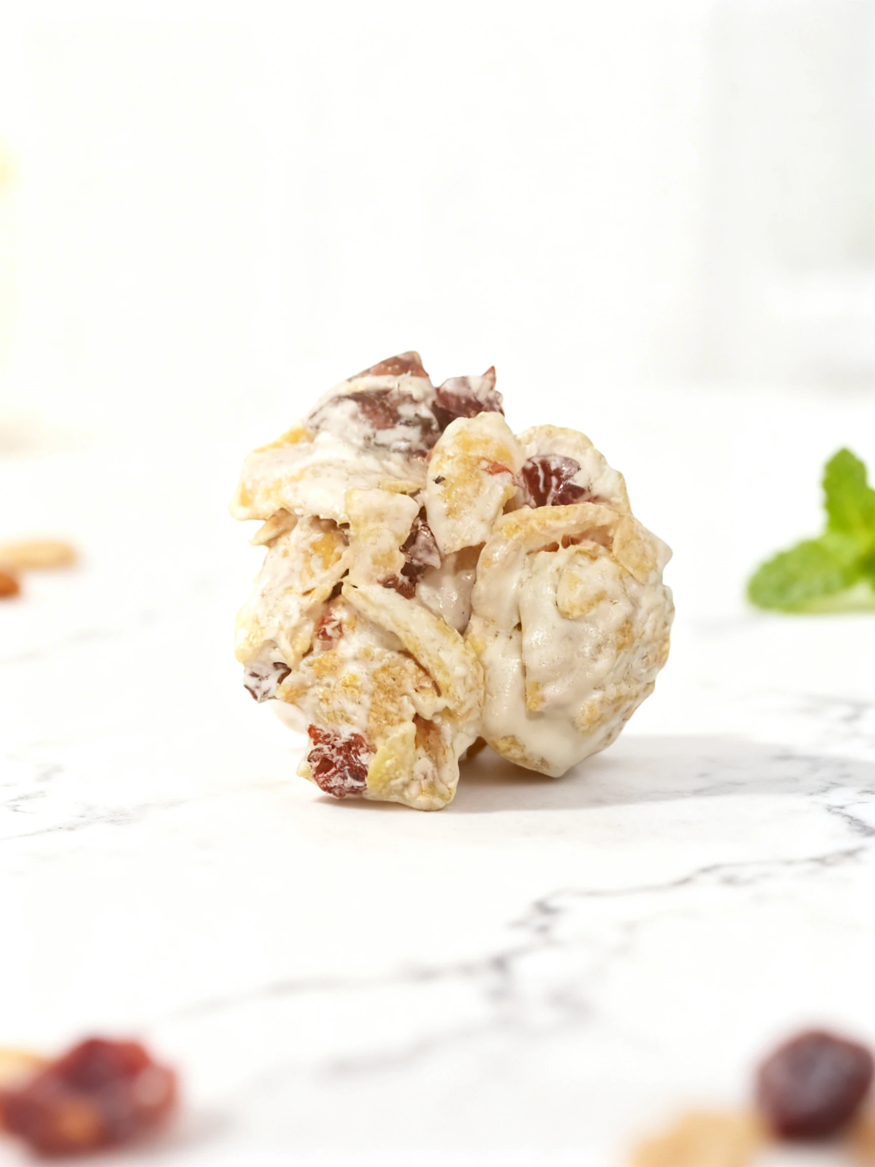 A cluster snack made of corn flakes and dried fruit coated in white chocolate or yogurt frosting.