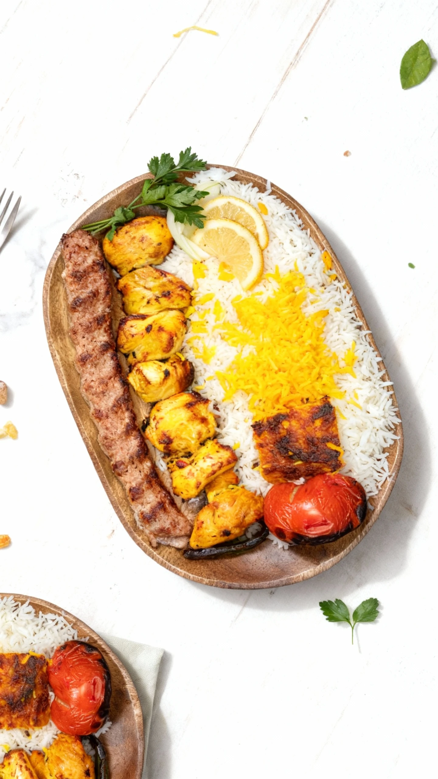 This combination kebab plate features a long ground meat skewer (Koobideh) and chunks of marinated chicken breast (Joojeh Kebab) served alongside steamed white