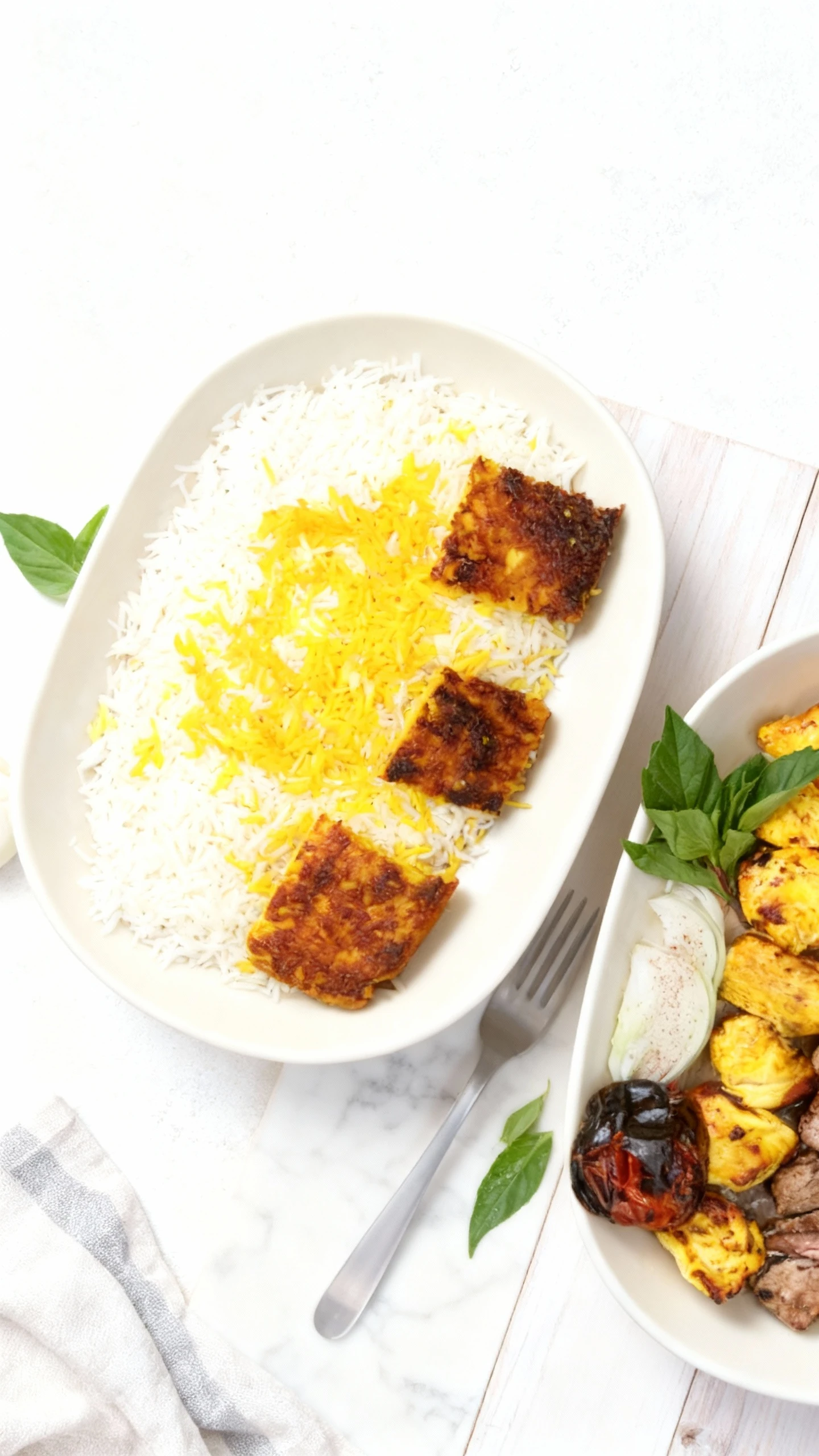 A combination Iranian kebab plate featuring skewers of grilled beef, marinated chicken chunks, and Kebab Kubideh (ground meat), served with grilled tomatoes, sl