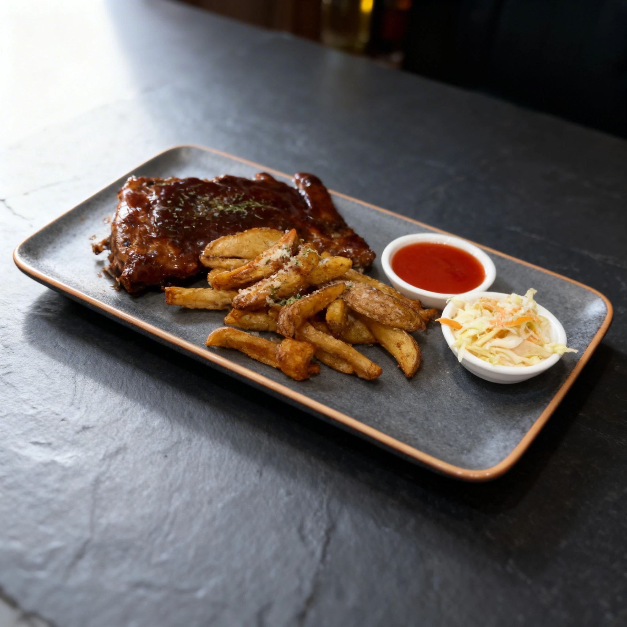 Barbecue pork ribs glazed in thick sauce served with potato wedges, a small dish of coleslaw, and a side of red dipping sauce.