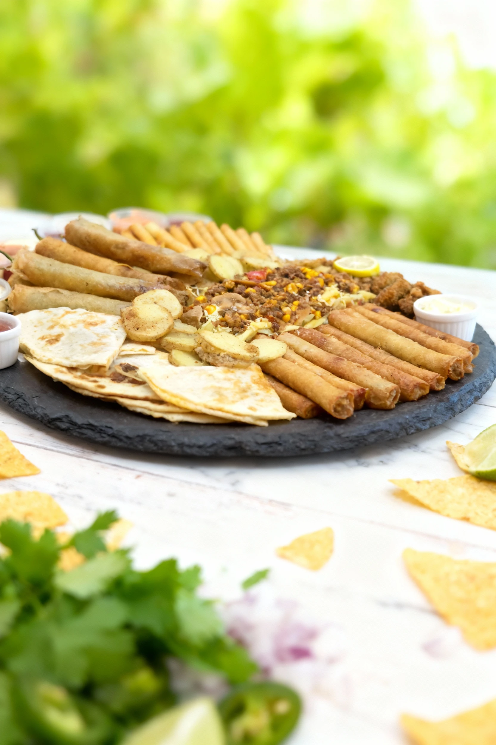 A large mixed platter featuring fried long rolls (some appearing to be chili peppers), crispy thin sticks, deep-fried battered pieces, and sliced pan-fried pota
