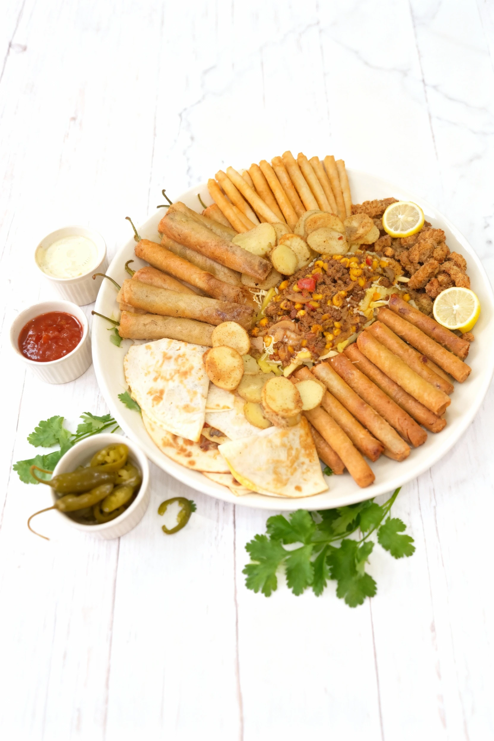 This is a large platter of assorted appetizers featuring sections of sliced quesadillas, various crispy fried rolls (like spring rolls or flautas), fried breads