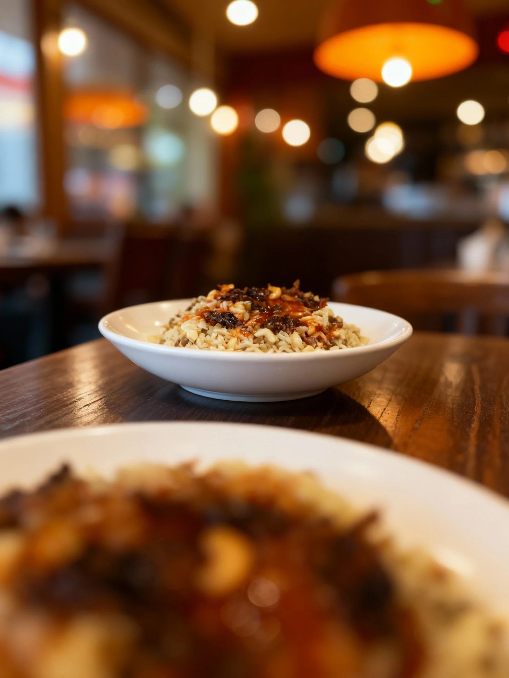A generous serving of Koshari, an Egyptian dish consisting of rice, lentils, and tubular pasta, topped with a bright orange-red sauce and a mound of dark, crisp