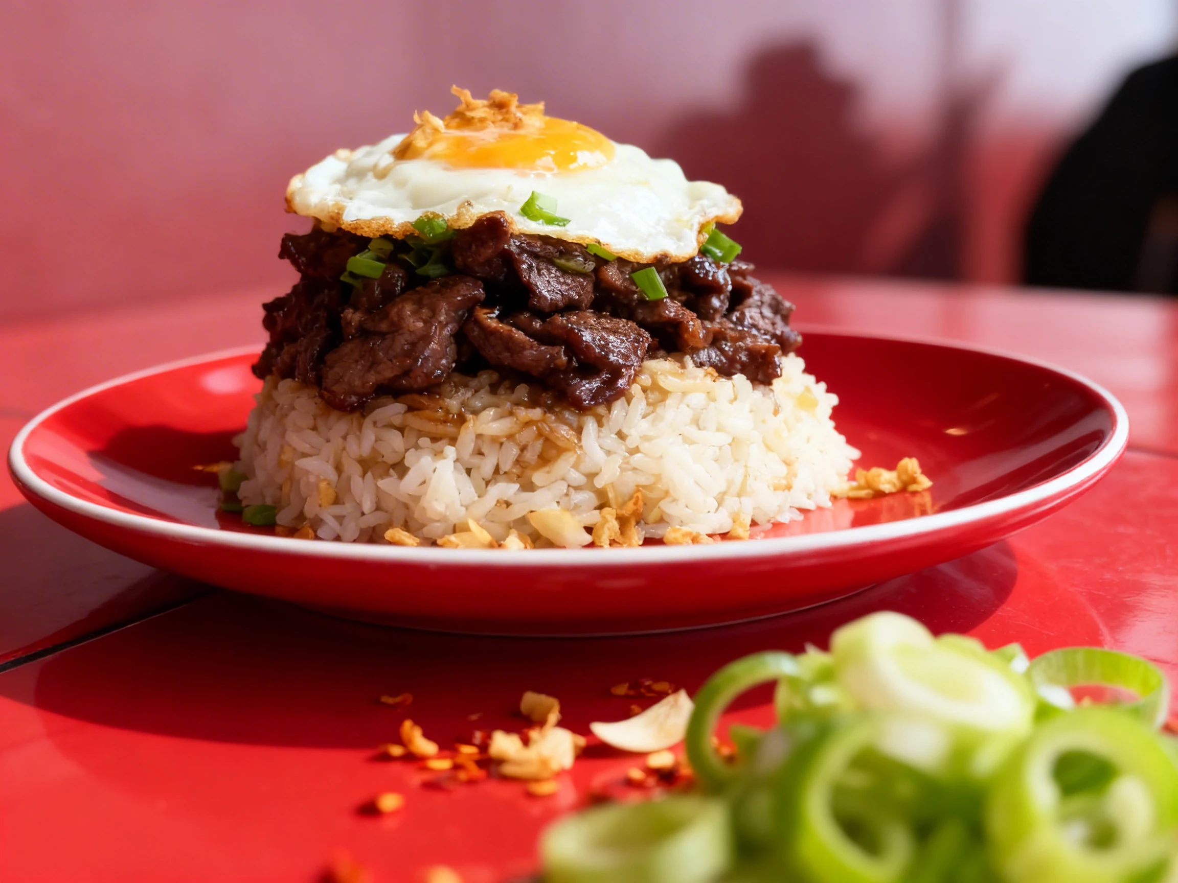 Beef tapa garnished with sliced green onions, served with garlic fried rice topped with toasted garlic and a sunny-side-up egg.