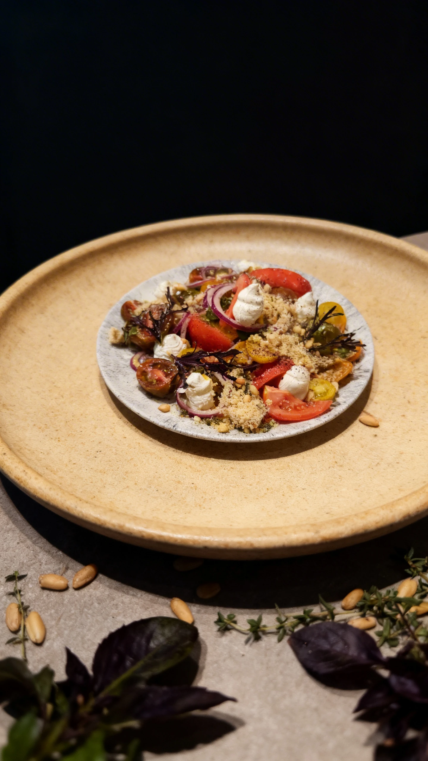 Heirloom tomato salad with red onion rings, whipped cream cheese dollops, pine nuts, and a fine crumble topping.
