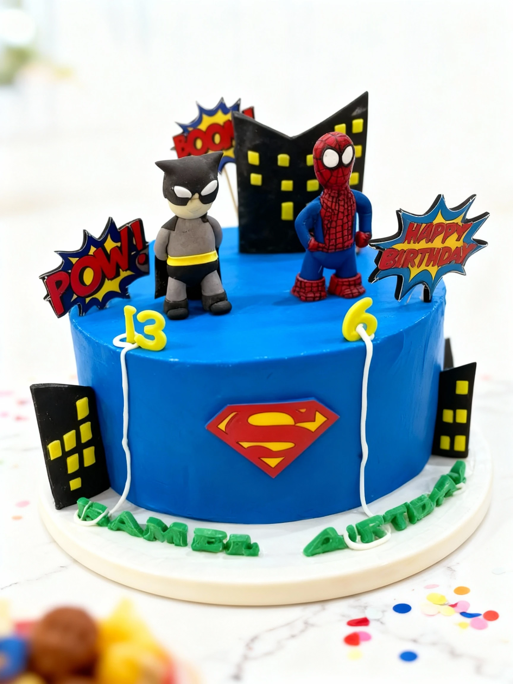A round, bright blue frosted birthday cake decorated with a superhero theme, featuring fondant or plastic figurines of Batman and Spider-Man, comic book-style w