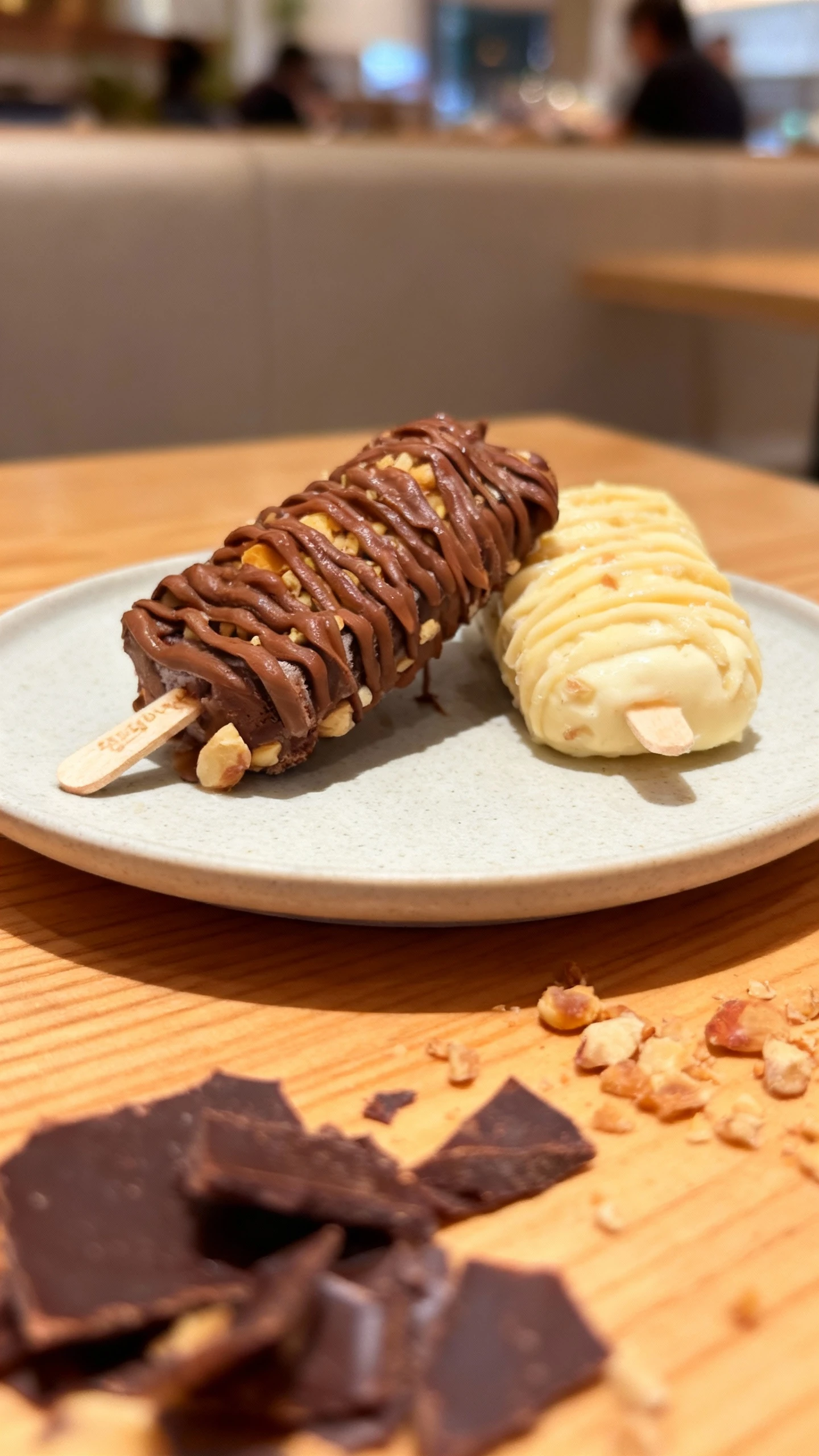 Gourmet chocolate and white chocolate popsicles topped with nut pieces and thick drizzles of chocolate sauce, served on wooden sticks.