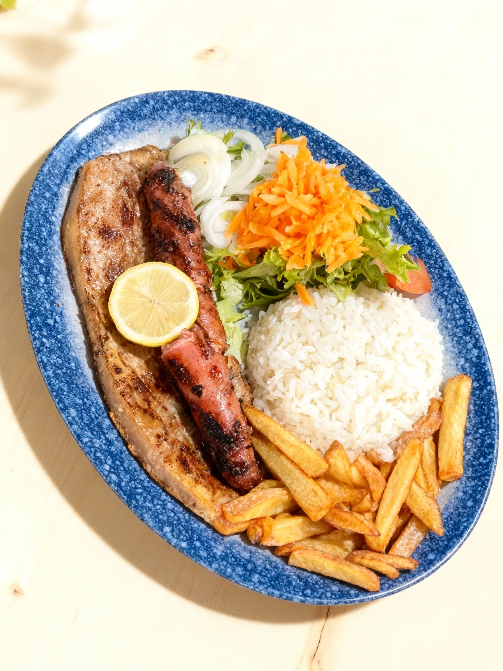 Grilled meat platter featuring a large pork chop and a charred sausage, served with a mound of white rice, golden French fries, and a fresh salad of shredded ca