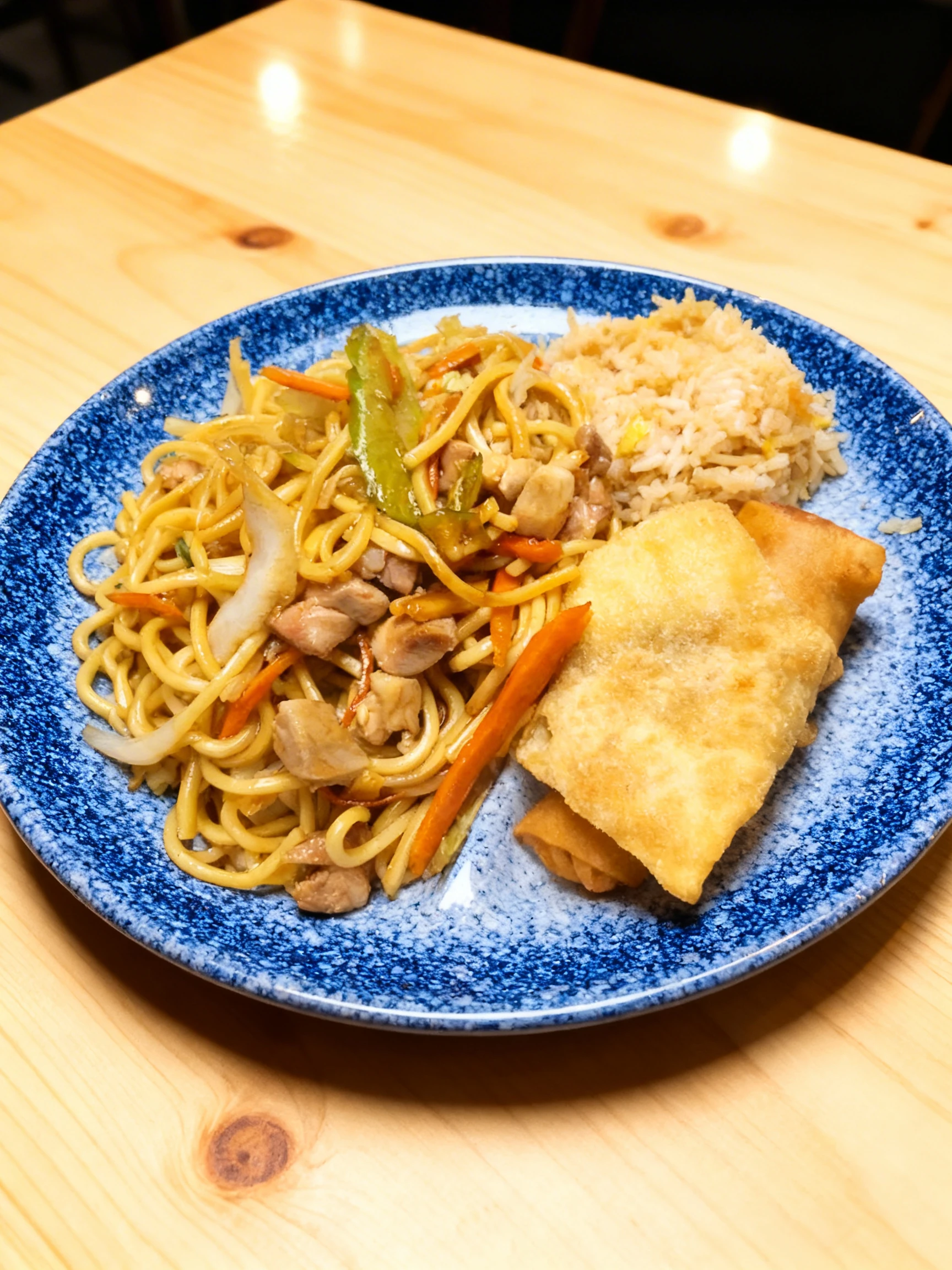 A Chinese-style combo platter consisting of chicken lo mein with stir-fried vegetables, fried rice, and a fried wonton with a spring roll.