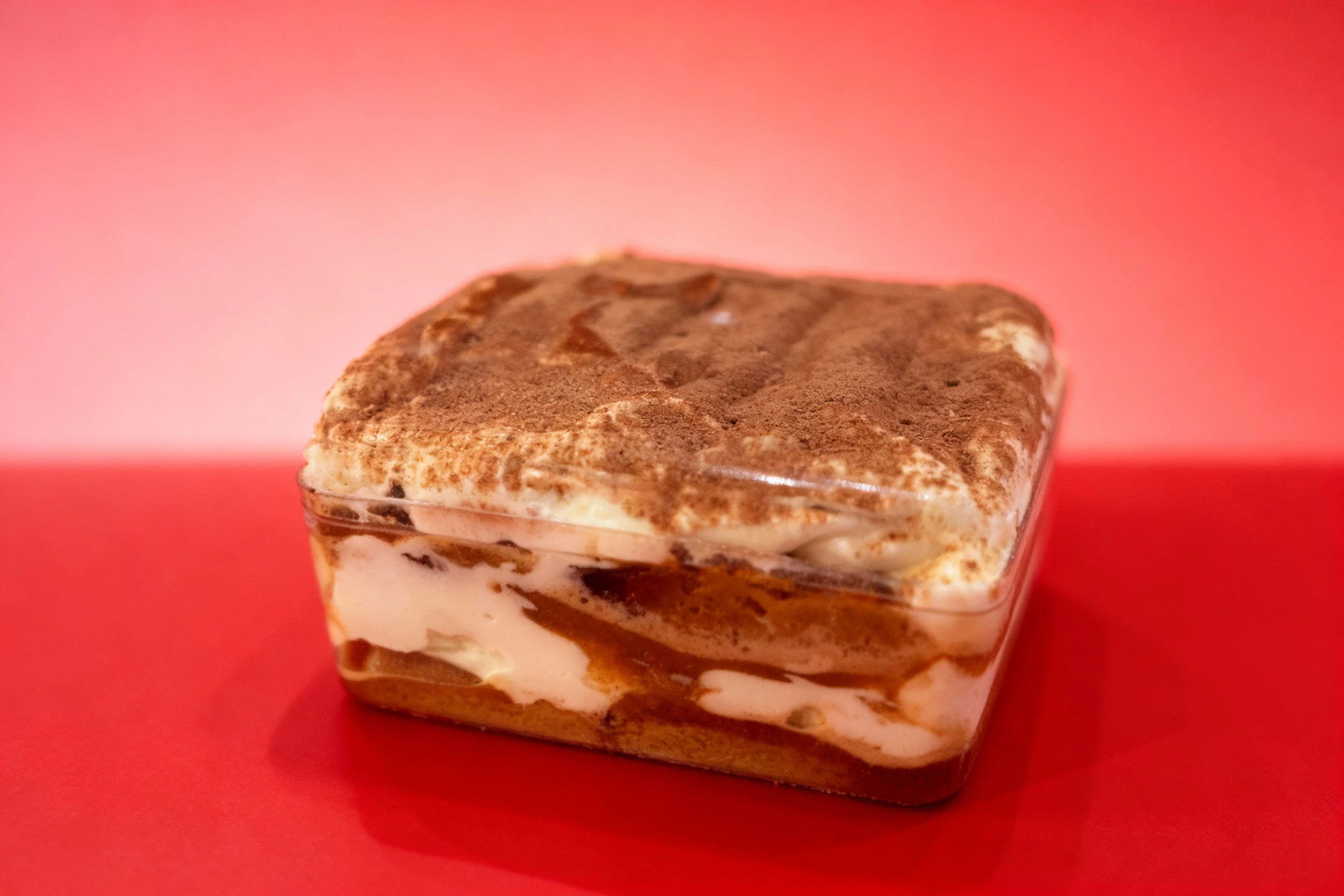 Layered Tiramisu dessert featuring creamy mascarpone and coffee-soaked elements, generously topped with a dusting of cocoa powder.