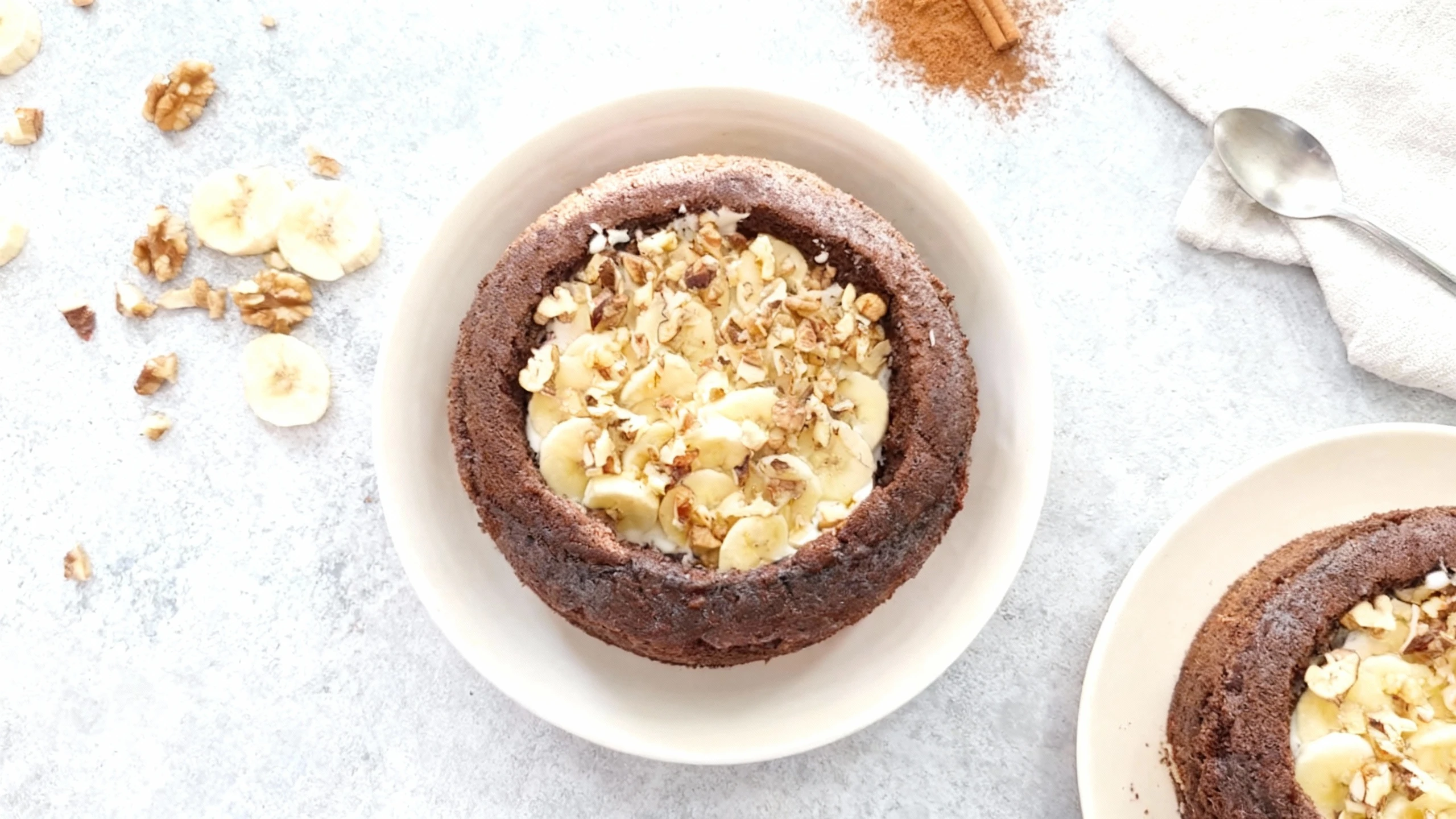 A deep, dark chocolate cake or brownie bowl filled with a creamy layer, topped generously with fresh banana slices and chopped walnuts.
