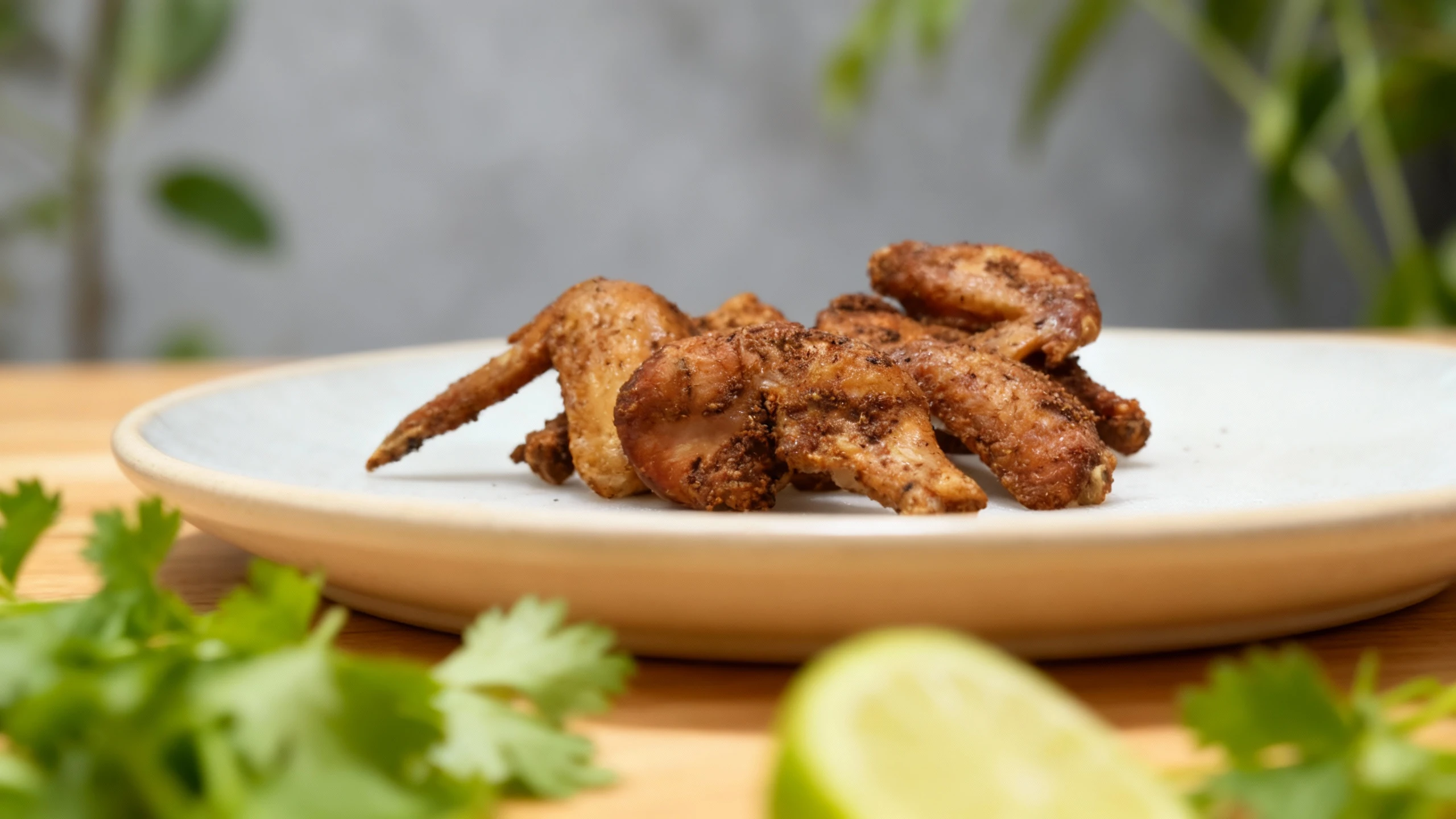 Seasoned chicken wings, consisting of wingettes and drumettes, heavily coated in a dark, savory dry spice rub.
