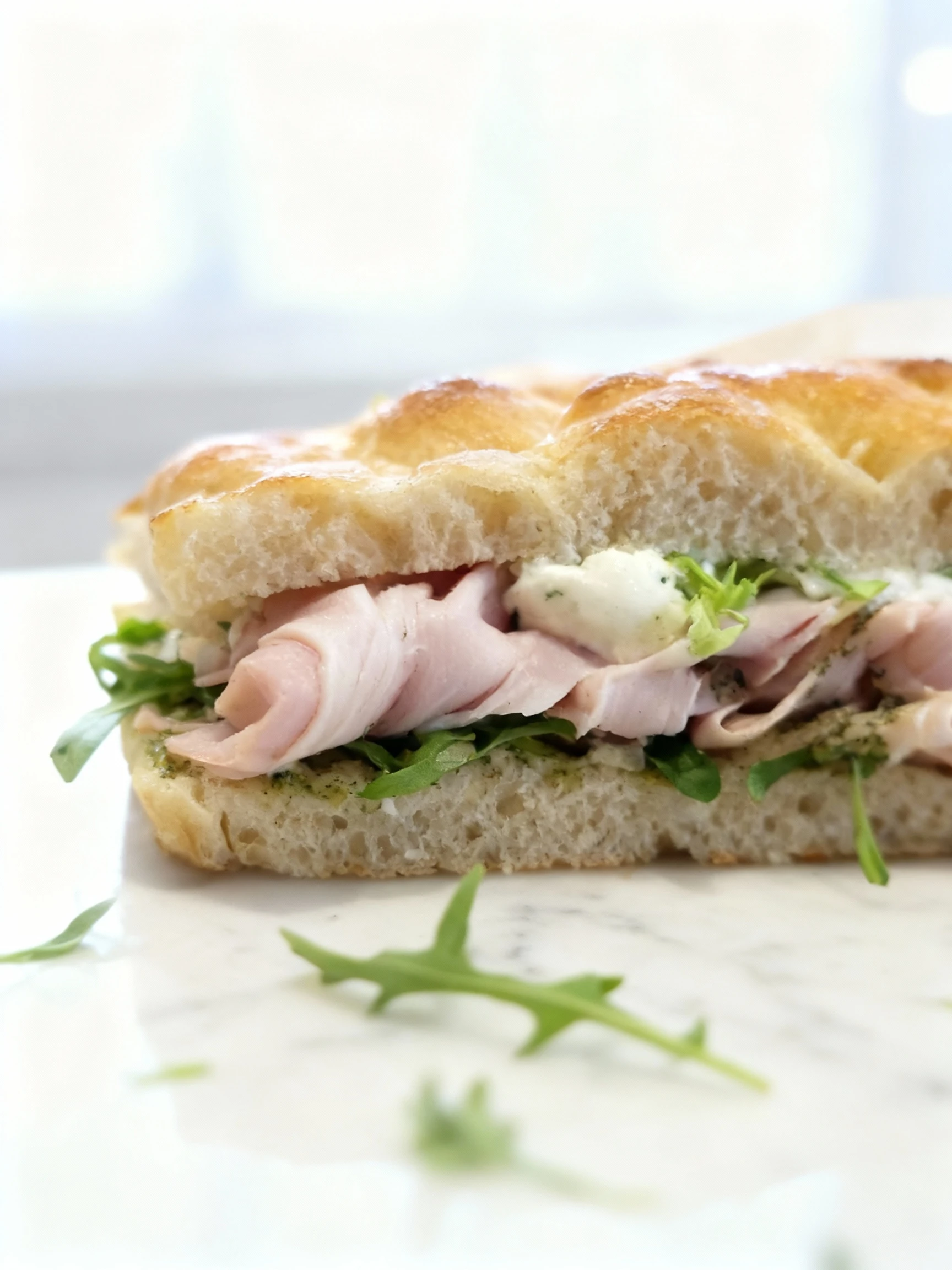 Focaccia sandwich filled with thinly sliced ham, fresh arugula, and herb cream cheese.