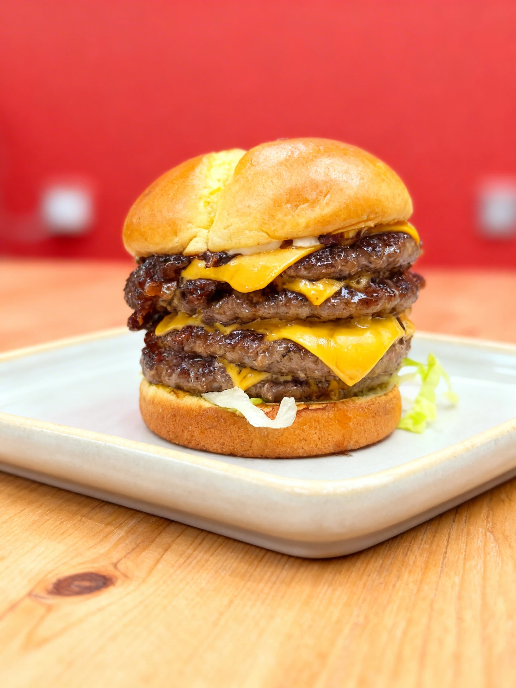 A quadruple beef patty cheeseburger on a brioche bun with melted american cheese and shredded lettuce.