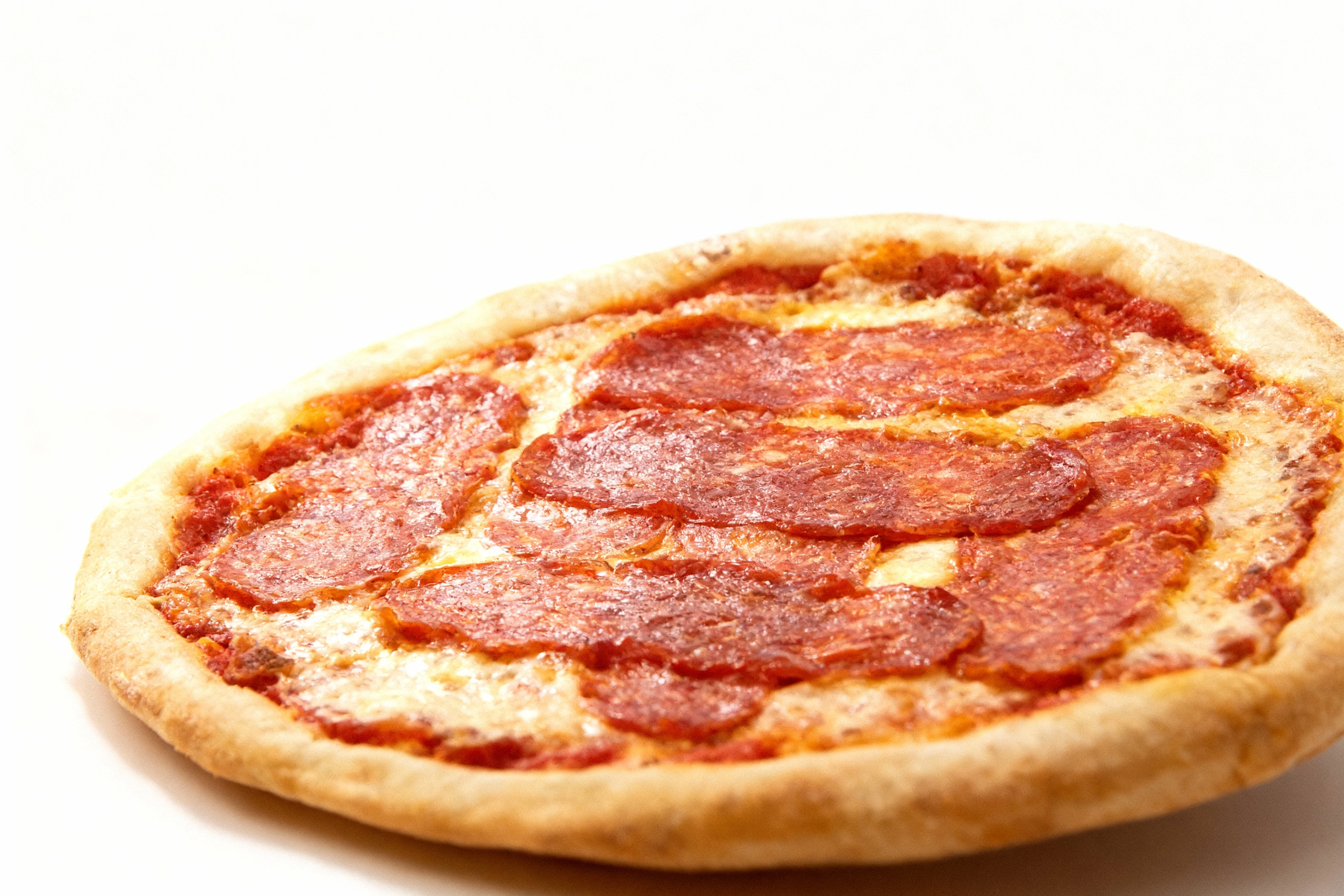 A whole pepperoni pizza topped with large, thin slices of salami over melted mozzarella and tomato sauce.