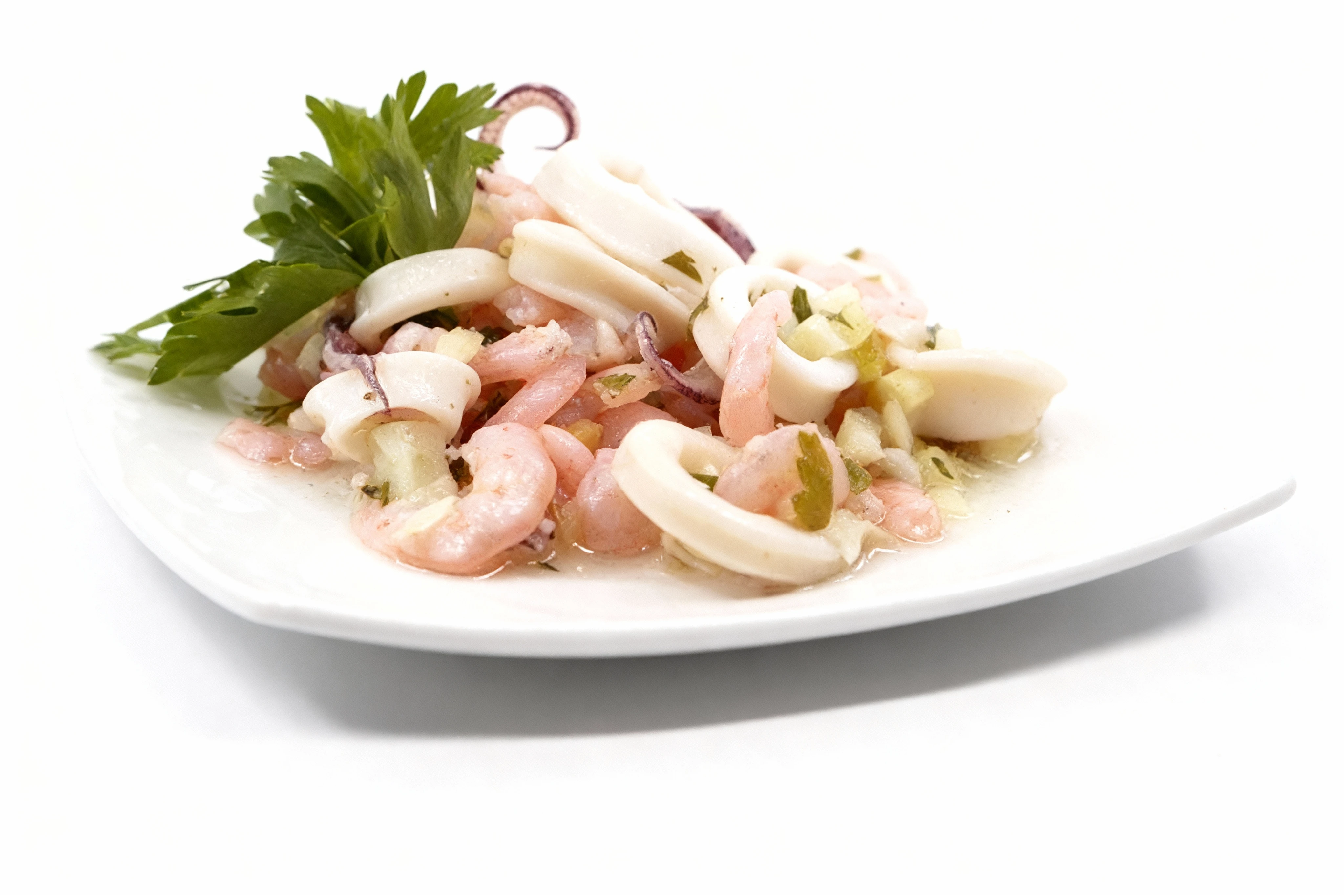 Seafood salad featuring cooked shrimp, calamari rings, and tentacles tossed with minced vegetables and garnished with fresh flat-leaf parsley.