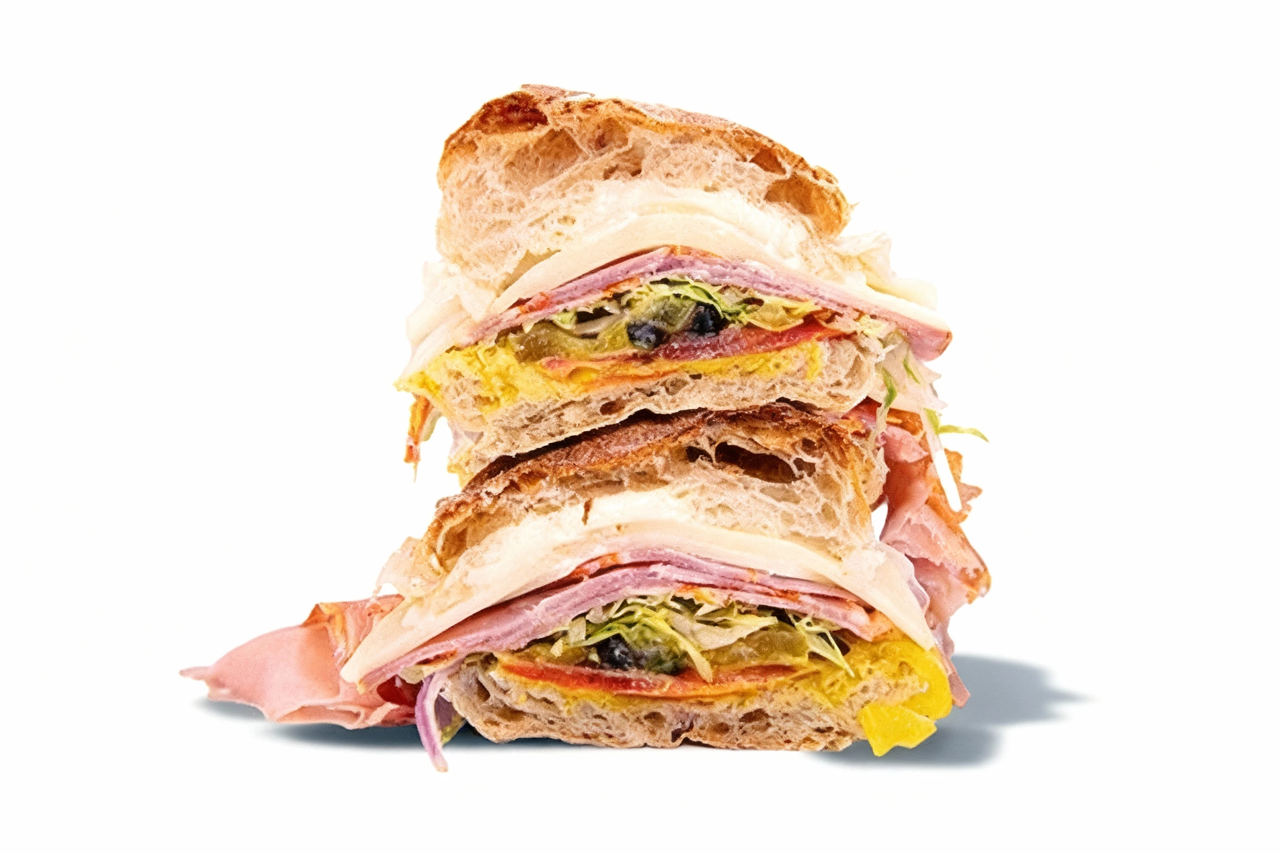 A stacked Italian sub sandwich featuring crusty ciabatta bread filled with layers of sliced ham, salami, provolone cheese, shredded lettuce, and yellow peppers.