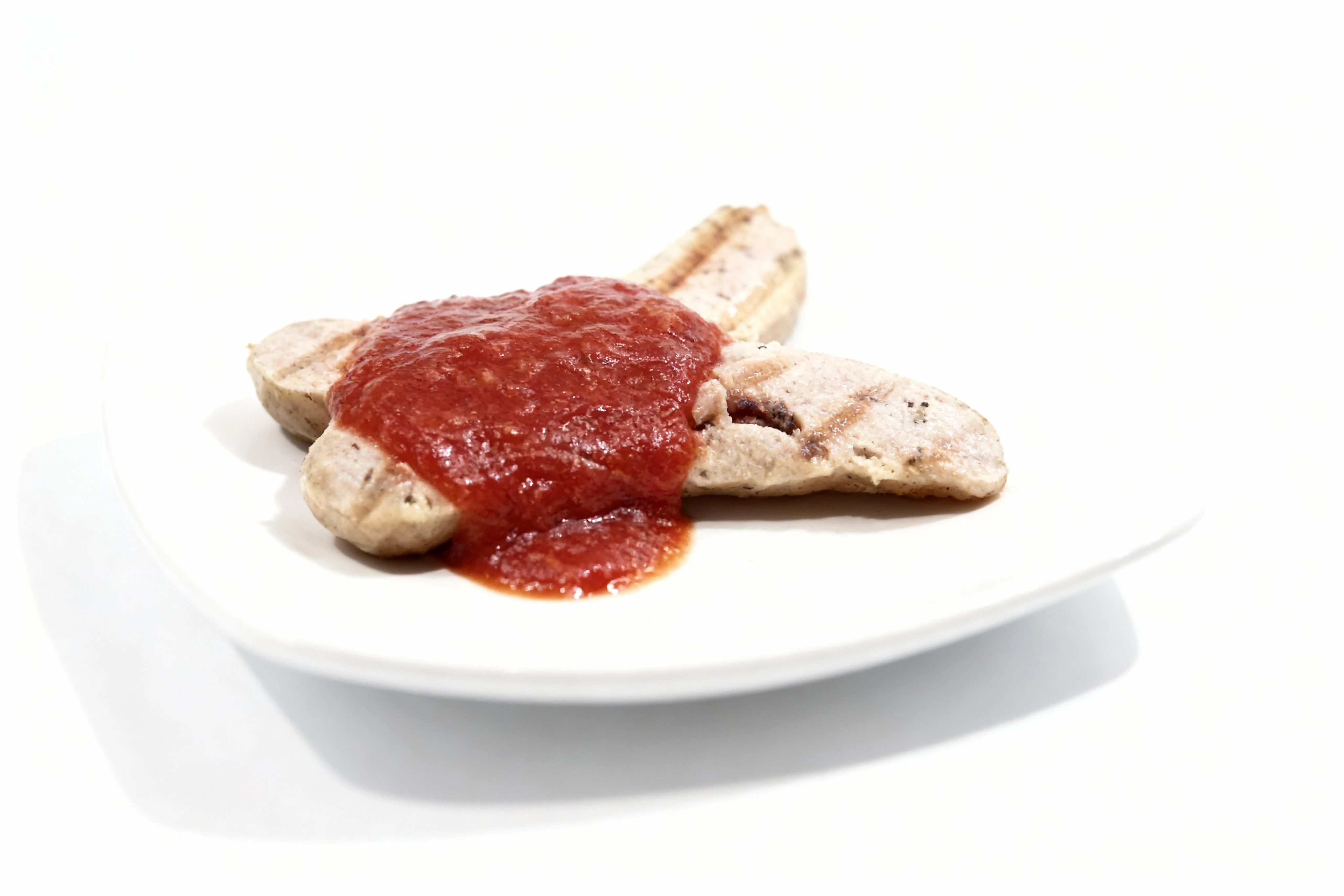 Grilled bratwurst or sausage halves topped with a thick tomato-based sauce or curry ketchup.