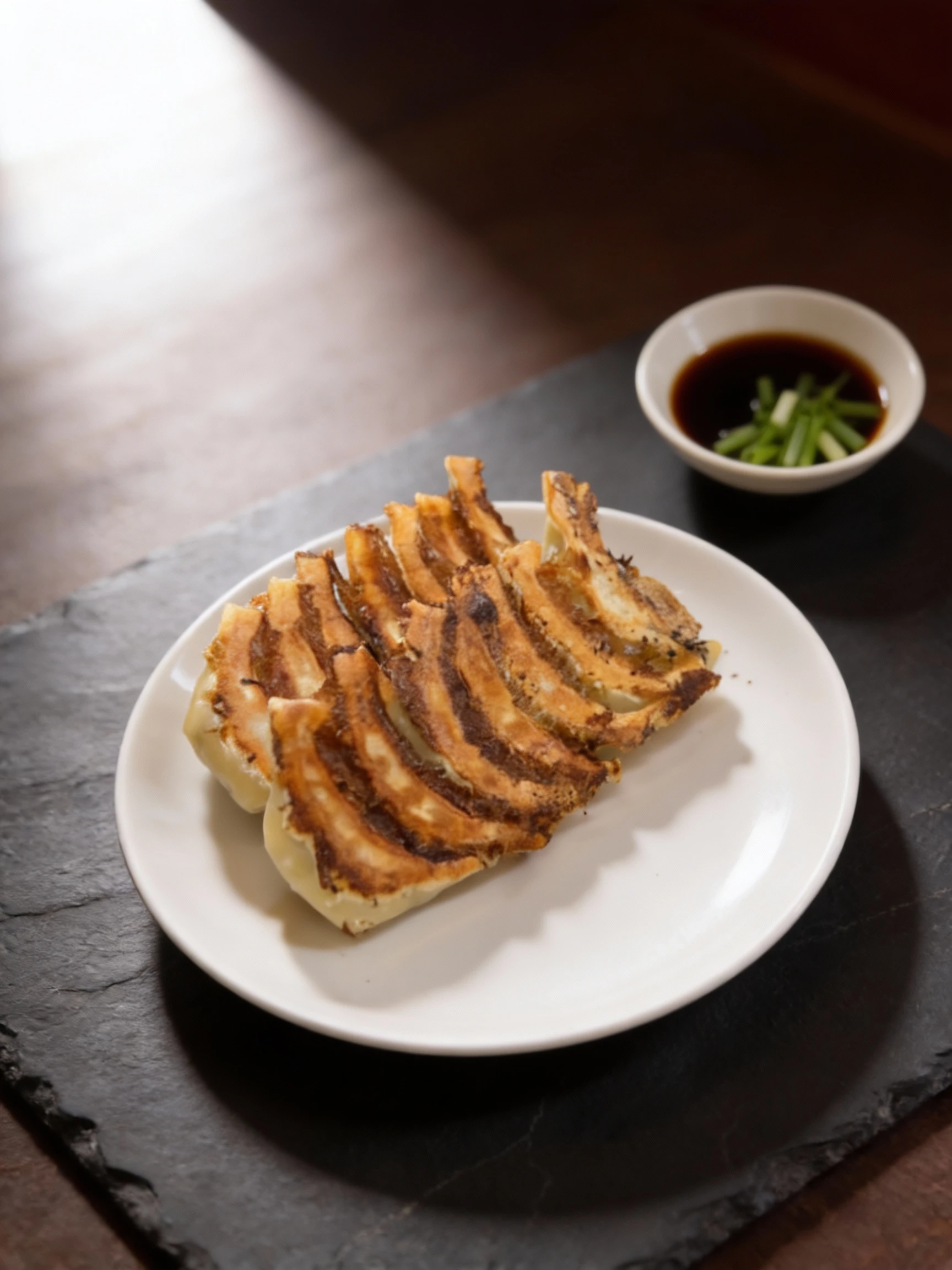 A serving of pan-fried gyoza (Japanese dumplings) presented linked together in a fan shape on a white plate, featuring a heavily browned and crispy bottom crust