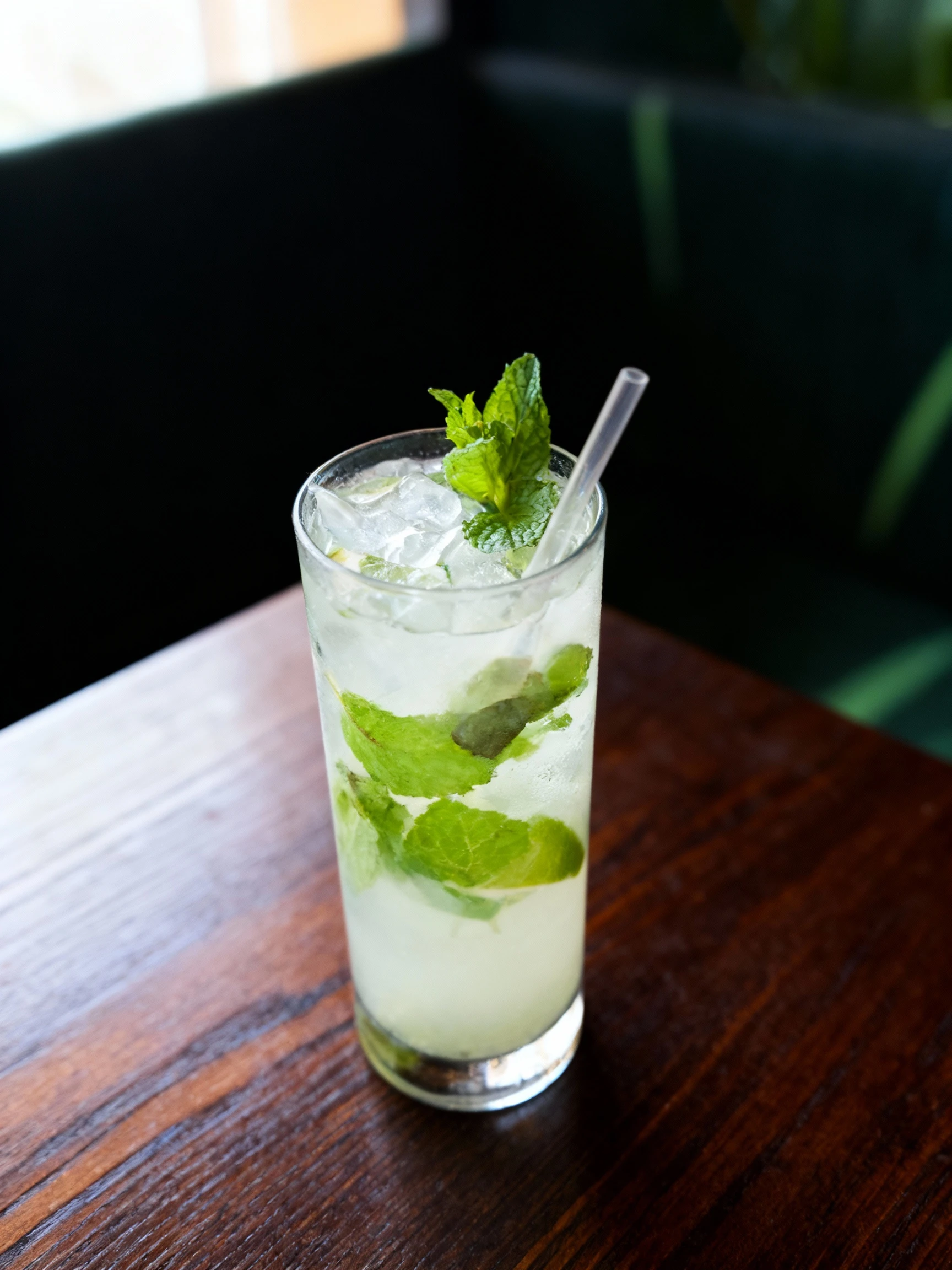 A Mojito cocktail served in a highball glass with fresh mint leaves, lime juice, and ice.
