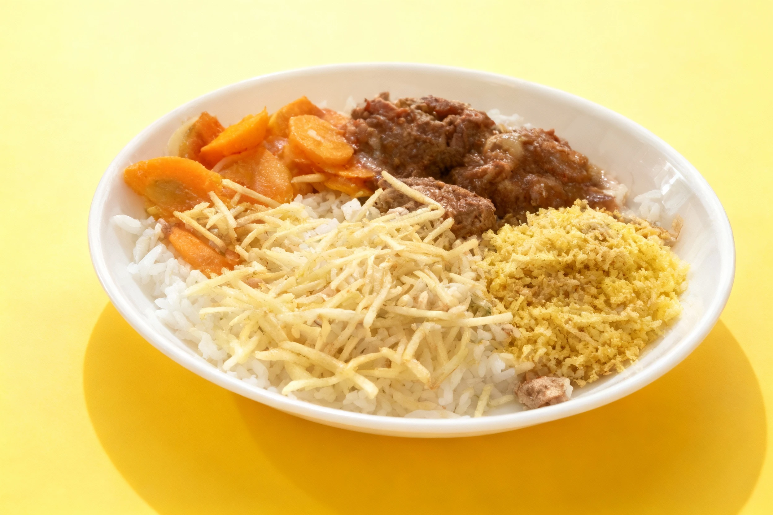 A plate of white rice topped with a brown meat stew (possibly beef) and sliced carrots, accompanied by a side of shoestring potato fries (batata palha) and toas