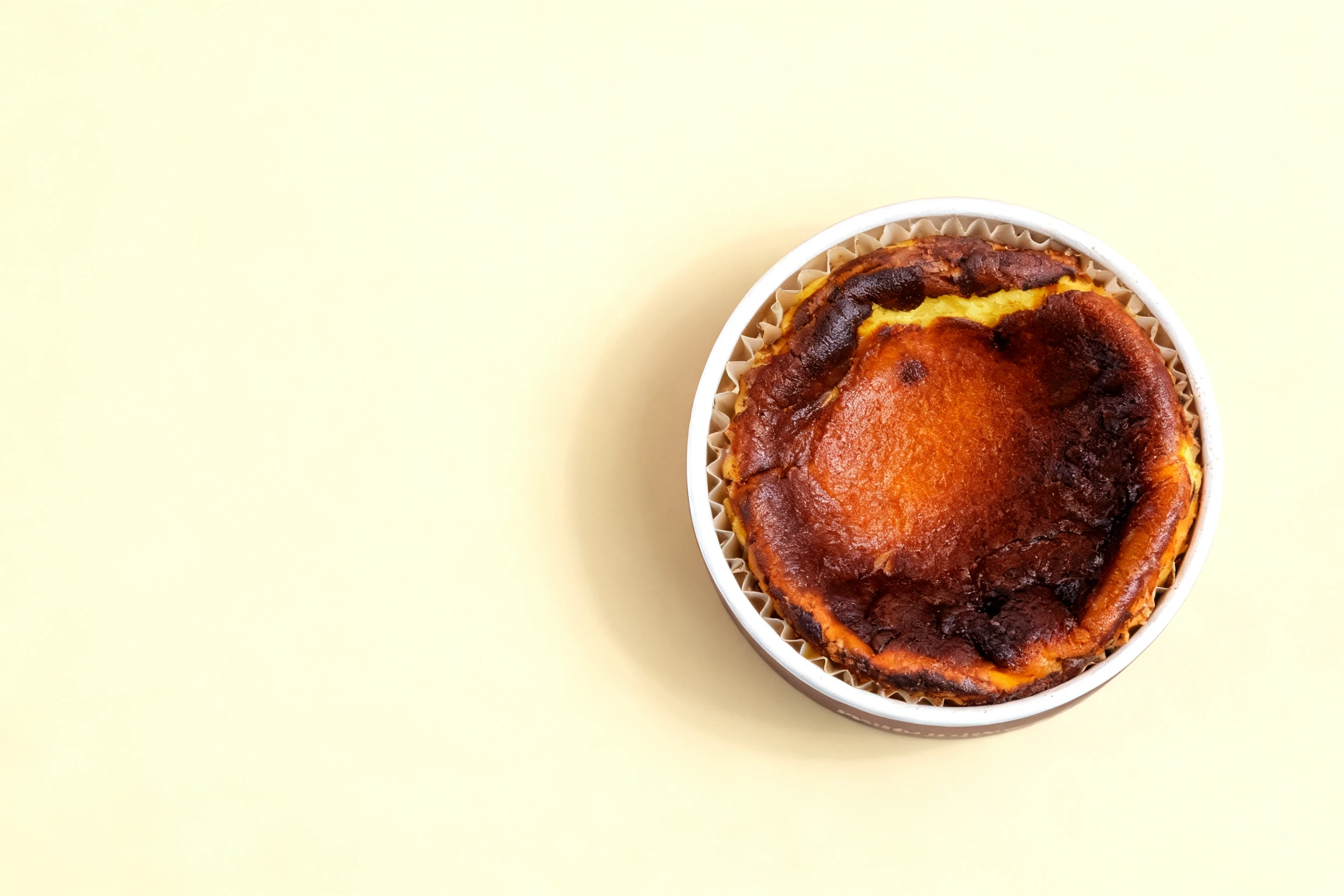 A whole Basque burnt cheesecake with a dark caramelised top sitting in its paper liner.