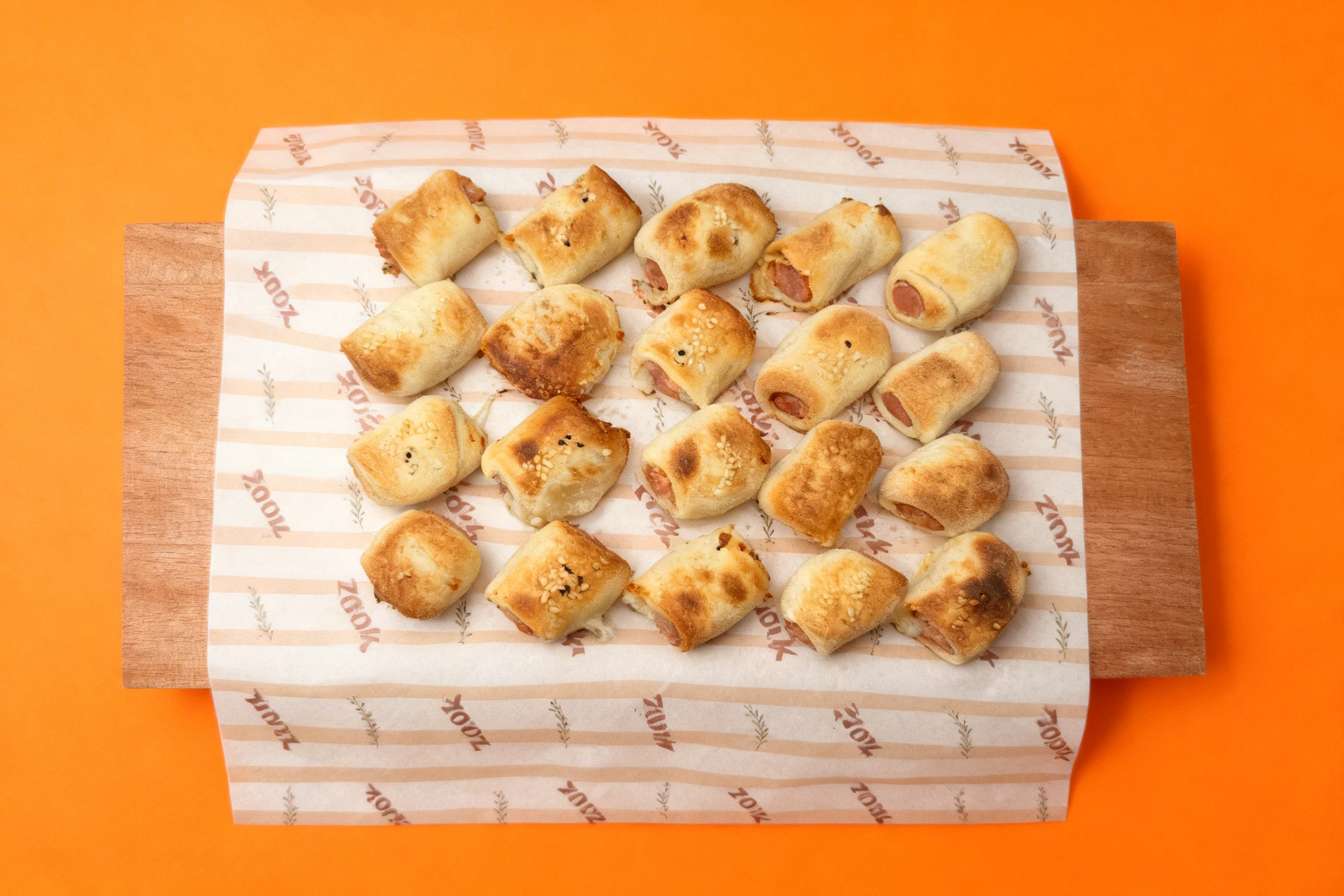 Mini sausage rolls with sesame seeds baked in golden-brown pastry shells.