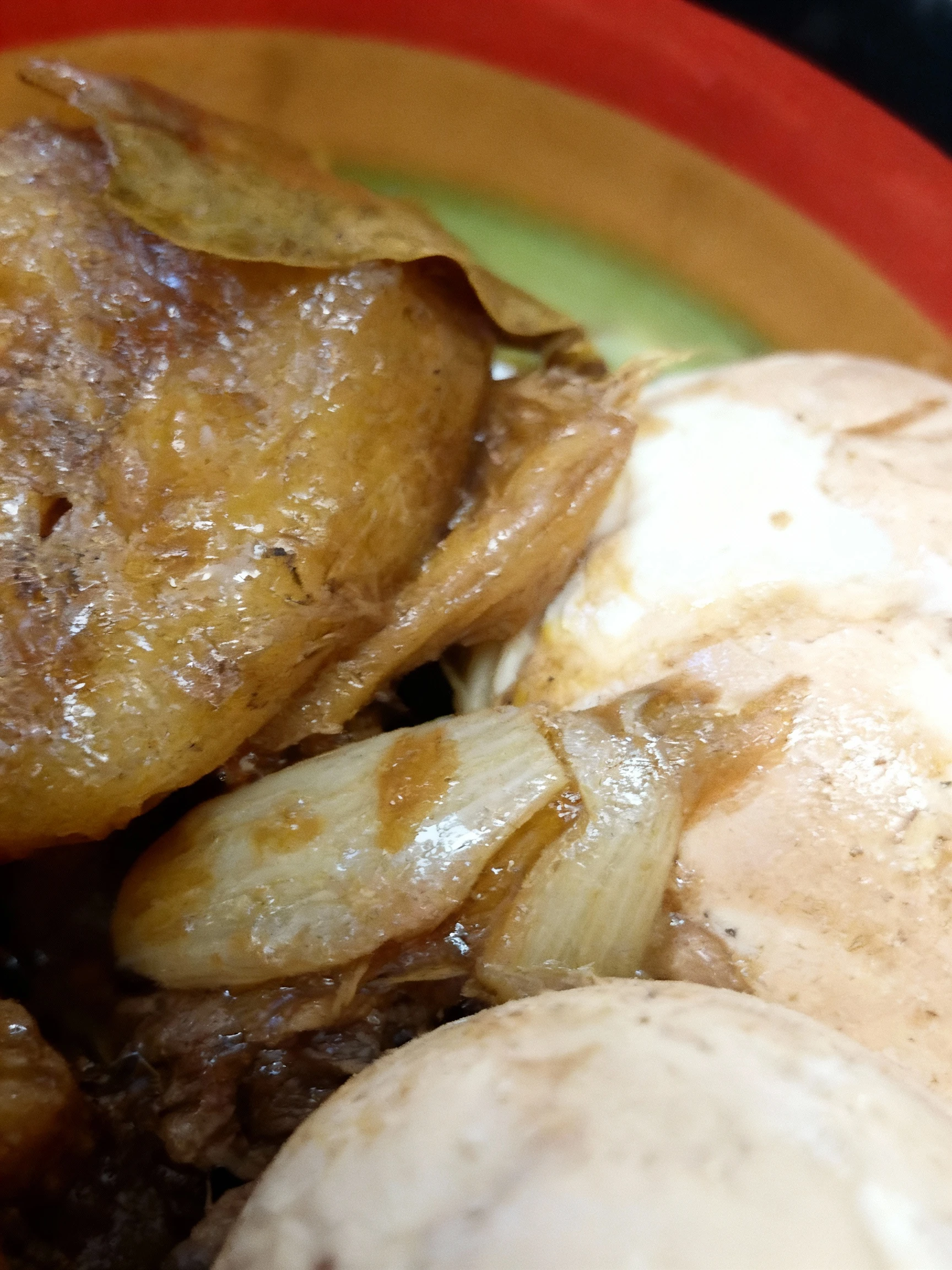 A hearty stew featuring large chunks of braised meat (likely pork or chicken) and potatoes, along with two whole soy-marinated hard-boiled eggs, all coated in a