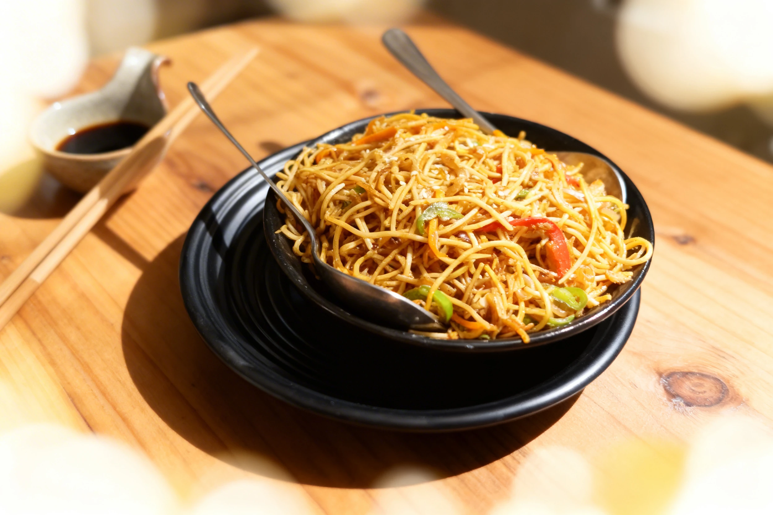 Vegetable stir-fry noodles with sliced bell peppers, onions, and carrots, topped with sesame seeds.