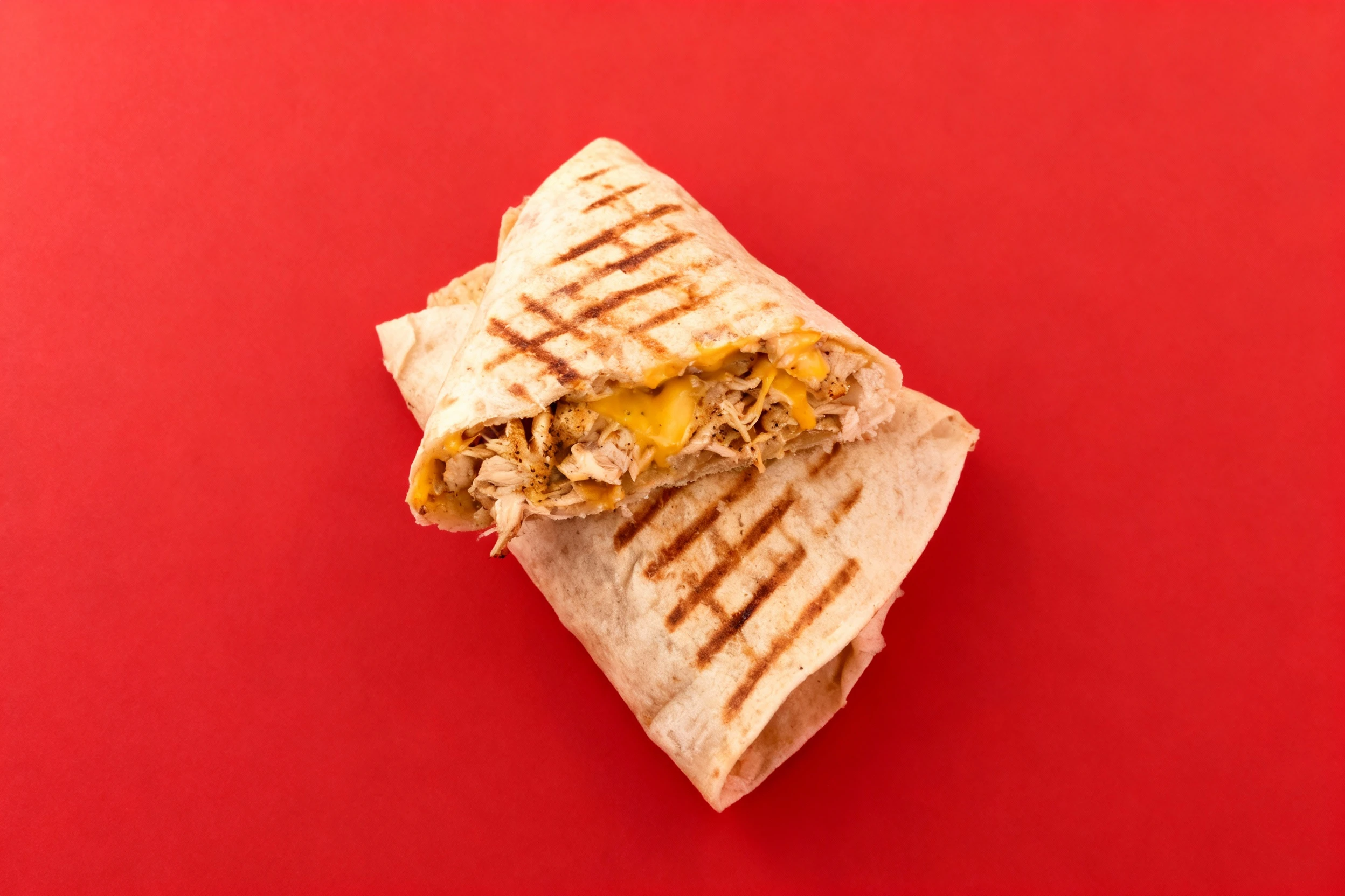 Toasted chicken wrap with melted cheddar cheese and seasoned pulled chicken inside a grilled flour tortilla.