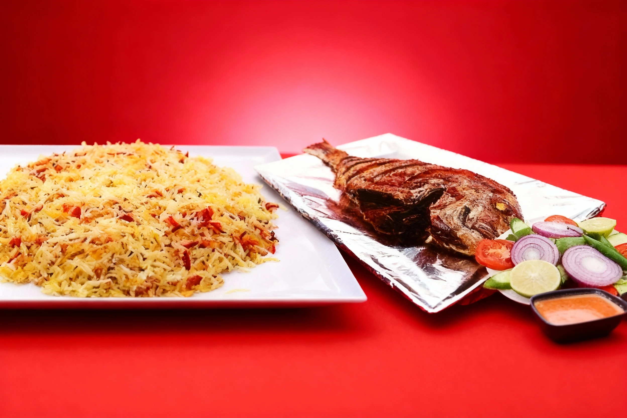 This Biryani Rice with Fish meal features a large portion of spiced rice served alongside a whole roasted fish resting on aluminum foil. The components are garn