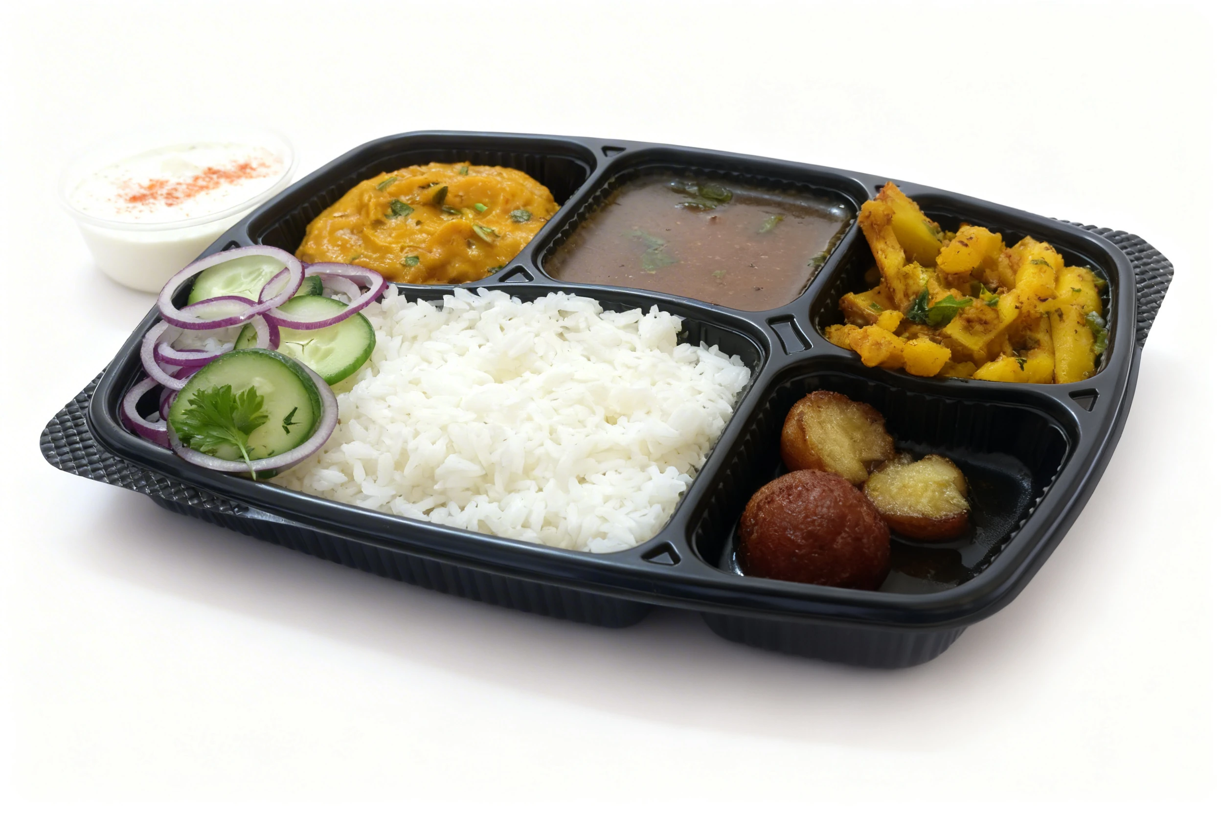 Indian thali meal featuring white rice, yellow dal, vegetable curry, sauted potatoes, and gulab jamun in a black tray, accompanied by raita and fresh salad.